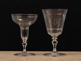 two empty wine glasses sitting on top of a table next to each other
