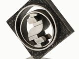 une photo d'une sculpture métallique représentant le symbole du dollar, dans une place