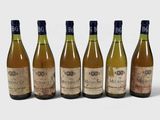 six bouteilles de vin sont alignées sur une surface blanche
