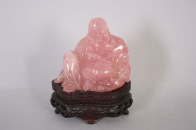 une statue rose représentant une personne assise sur une table