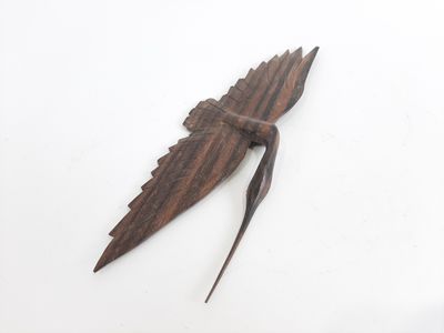 un oiseau en bois posé sur une surface blanche