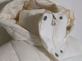 a white down jacket with a hood on a white wall