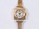 a gold wrist watch with a white face on a white surface