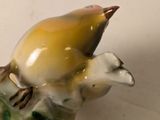 a small figurine of a bird sitting on a branch