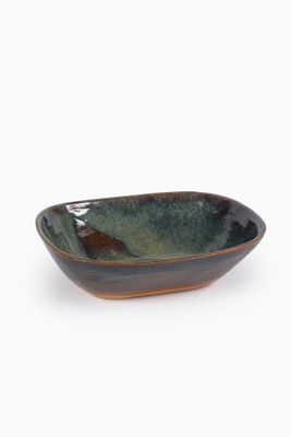 un bol marron et vert posé sur une surface blanche