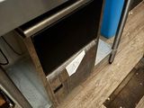 une table en acier inoxydable avec une poubelle bleue posée en dessous