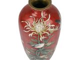 a red vase with flowers and birds painted on it
