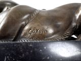 a statue of a horse laying down on a black base