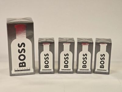 four bottles of boss cologne sitting next to each other on a white surface