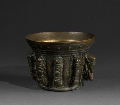 an image of a bronze cup with a handle on a gray surface