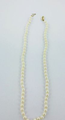 a white pearl necklace with a gold clasp