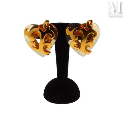 une paire de boucles d'oreilles ornées de motifs dorés et rouges, posées sur un support noir