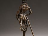a bronze statue of a woman with a cane and a hat