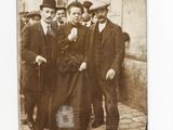 photograph of a group of men standing next to each other in front of a building