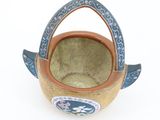 a small basket with a handle on a white surface