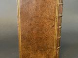 an old book with a brown cover sitting on top of a table