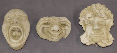 trois têtes sculptées représentant un homme et une femme, posées sur une table