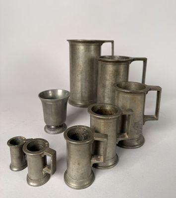 a lot of silver cups and mugs sitting on a table