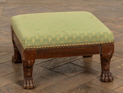 un petit repose-pieds sur lequel est posé un coussin vert