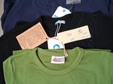 a pile of shirts with tags on them on a shelf