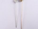 pair of silver and gold pins with a knot on them