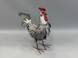 un coq en métal posé sur une surface blanche