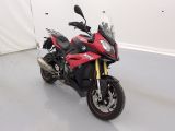 une moto rouge et noire garée dans une pièce blanche