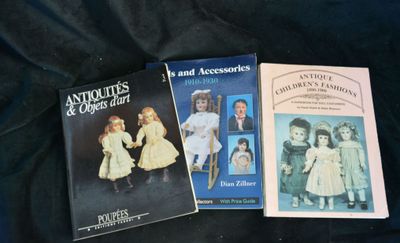 three books of antique dolls and accessories on a black cloth