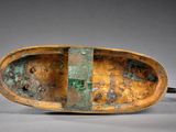 an old wooden boat sitting on top of a table next to a gray wall