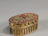 une image représentant une boîte dorée et rouge posée sur une table
