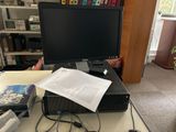 un écran d'ordinateur posé sur un bureau couvert de papiers