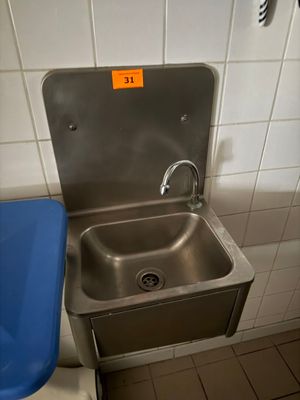 a blue trash can next to a sink in a public restroom
