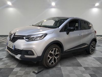 Une voiture argentée est garée dans une pièce au sol en damier.