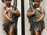 deux statues en bronze représentant un garçon et une fille, posées sur une table