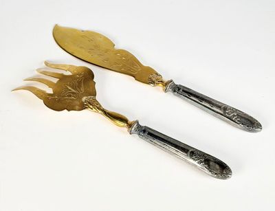 une paire d'ustensiles de service en argent et plaqué or sur fond blanc