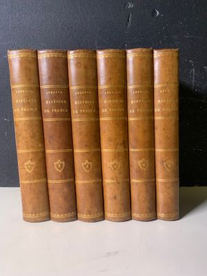 six livres anciens reliés en cuir, alignés sur une table blanche