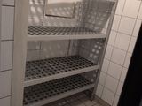 a white tiled bathroom with shelves and tiled floor