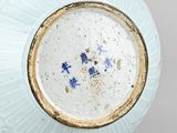 a white vase with blue flowers in it on a table