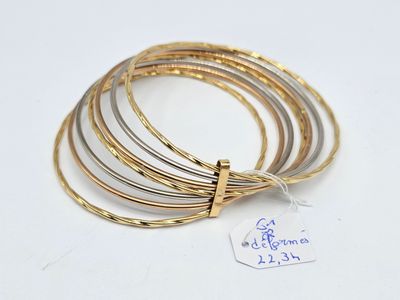quatre bracelets rigides en or et en argent posés sur un fond blanc