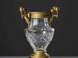 un vase plaqué or muni de deux anses et posé sur un socle