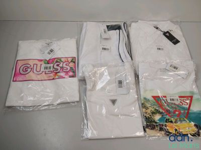 Trois t-shirts blancs sont posés les uns à côté des autres sur une table.