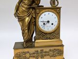 a statue of a woman holding a clock on a table