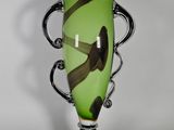 un vase vert avec une anse noire sur fond blanc