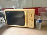 a yellow microwave sitting on a counter next to a bottle of water