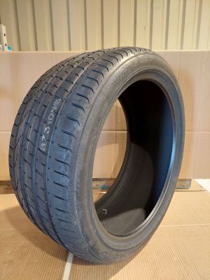 un gros plan d'un pneu posé sur une surface en carton, avec une boîte en carton en arrière-plan