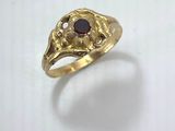 a close up of a gold ring with a red stone in it