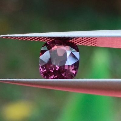 Quelqu'un est en train de tailler un diamant rose à l'aide d'une paire de pinces.