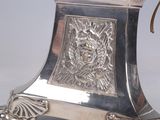 a silver clock with a lion head on top of it
