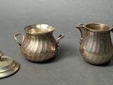 a silver pitcher and a silver cup next to each other