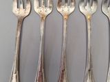 six forks and a knife are lined up on a table